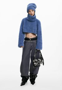 Hele sinine karvane lühike kootud kampsun koos kaelusega, kombineeritud tumedate laiade pükste ja mustade teravate saapadega, kaasas musta mustriga käekott.