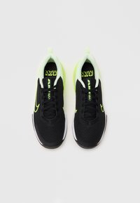 Black mesh athletic shoes with white and neon green accents, featuring a rounded toe, lace-up design, and cushioned soles.