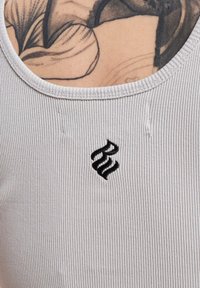 Lichtgrijze geribde tanktop met een ronde halslijn, voorzien van een klein zwart geborduurd logo aan de linkerkant.