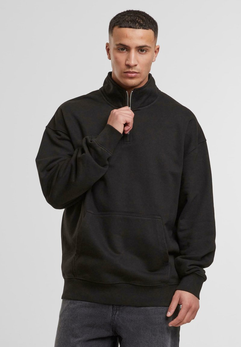 Black zip-neck sweatshirt with a relaxed fit, long sleeves, and a front kangaroo pocket. Made from a soft, textured fabric.