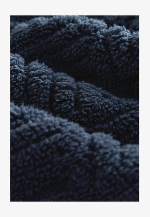 Tamsiai mėlynas pūkuotas audinys su minkšta, tekstūrine paviršiaus struktūra, turintis gilias, pūkuotas skaidulas bangų raštu. Puikiai tinka šilumai ir komfortui.