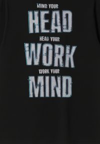 Czarna tkanina z pogrubionym, teksturowanym tekstem w odcieniach niebieskiego, zawierająca słowa „ZACHOWAJ OSTROŻNOŚĆ”, „ĆWICZ UMYSŁ” ułożone w stos.