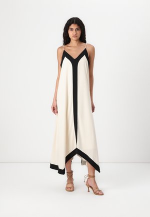 Robe légère sans manches avec un décolleté en V, présentant un corps principal crème et des accents géométriques noirs, longueur cheville, avec un ourlet légèrement asymétrique.