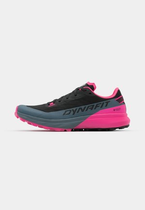 Sapatos de trail running com um superior preto com detalhes em rosa, uma entressola cinza, tecido texturizado e uma sola robusta para melhor aderência.