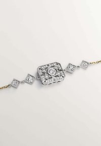 Pulsera de plata con un colgante central cuadrado que lleva una piedra redonda, rodeada de pequeñas piedras cuadradas, unidas por una cadena con acentos dorados.