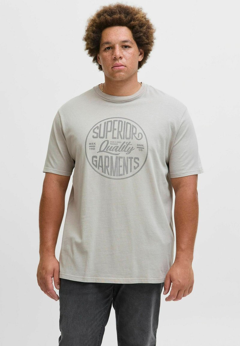 Hellgraues T-Shirt mit kurzen Ärmeln, das ein kreisförmiges Grafikdesign mit dem Text "Superior Quality Garments" in dunklerem Grau zeigt.