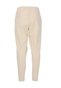 Beige tygbyxor med elastisk midja, avsmalnande ben och sidofickor. Slät textur utan dekor eller mönster.