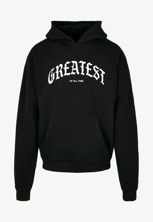 Svart hettegenser laget av bomull, med en frontlomme, ribbestrikkede mansjetter og nederkant, samt hvit tekst med «GREATEST OF ALL TIME» over brystet.