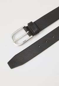 Curea din piele neagră cu cataramă metalică argintie gravată cu "BOSS", arătând mai multe gauri de ajustare pe un fundal alb.
