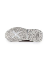 Suola di una scarpa realizzata in un materiale gommoso grigio testurizzato con macchie colorate, motivi contornati e un ritaglio centrale a forma di croce.