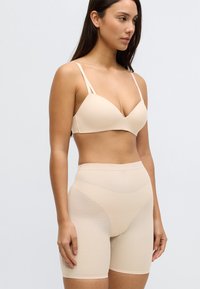 Sutien bej cu bretele subțiri și textură netedă, asortat cu pantaloni scurți bej cu talie înaltă, având un design elegant și un model subtil.