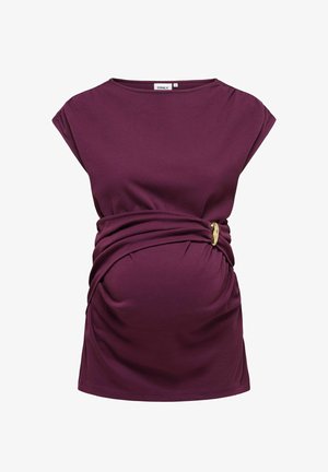 Vijolična nosečniška majica z okroglimi rokavi, nabranim materialom na trebuhu, ki je na strani pritrjen z zlatim zaponkom.