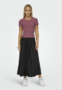 Fialový žebrovaný tričko s krátkými volánovými rukávy v kombinaci s černou plisovanou midi sukni a bílými teniskami. Ležérní outfit s kontrastními texturami.