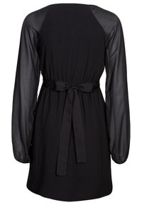 Svart klänning med en slät tygkropp och genomskinliga långa ärmar. Den åtsittande midjan med en knytdetalj ger struktur åt den lösa silhuetten.