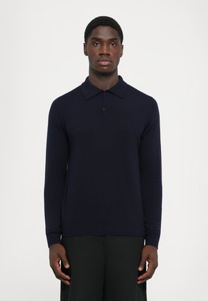 Marineblå langermet polo med strukturert strikkemønster, to-knapp placket og ribbede mansjetter. Ren, minimalistisk design uten aksenter.