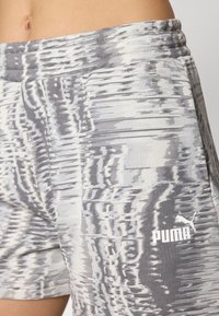 Calções atléticos cinza e brancos com padrão, com um cós elástico e um pequeno logótipo da Puma em branco no lado inferior direito.