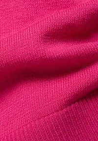 Geriffelter rosa Stoff mit strukturierter Oberfläche, der eine leuchtende Farbe und weiche Textur zeigt, mit deutlichen Linien und Falten für zusätzliche Dimension.