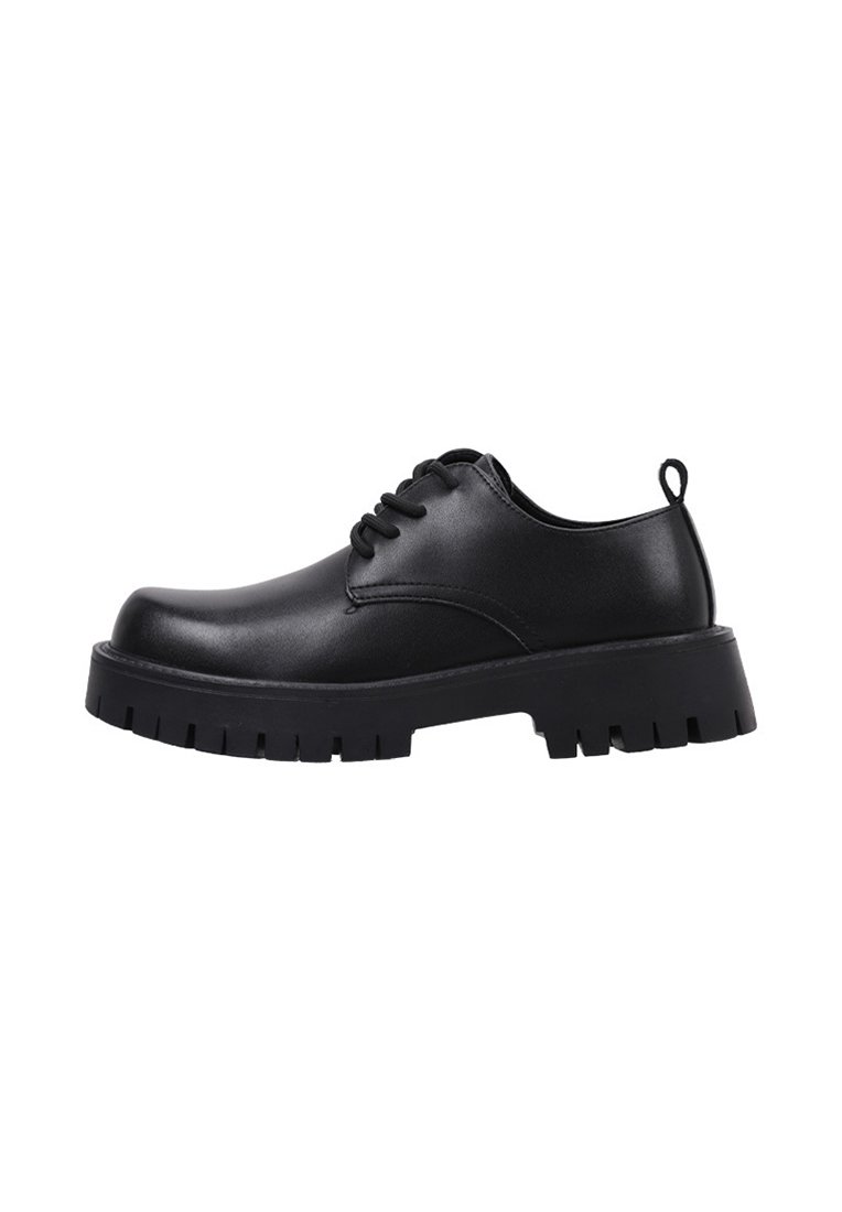 Zapatos negros con cordones que tienen un upper sintético liso, suela texturizada y resistente, puntera redonda y una tira en el talón para ponérselos fácilmente.