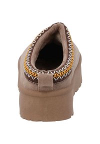 Brun mocka slip-on sko med rund tå; har vit och gul söm runt öppningen och en texturerad gummisula.