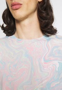 T-shirt à manches courtes marbré dans des teintes de rose pastel, bleu et jaune avec le logo Levi's. Tissu en coton doux, design col rond, coupe décontractée.