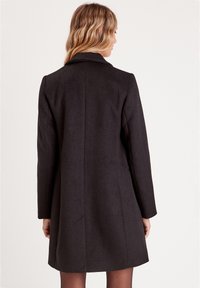 Black wool coat with a tailored fit, long sleeves, and a notched collar. Features a smooth texture and a mid-length cut.