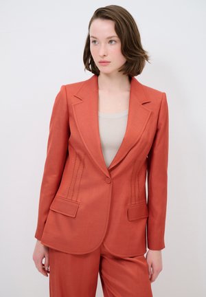 Roodbruine blazer met een gestructureerd ontwerp, voorzien van voorzakken en gedetailleerde stiksels langs de zijkanten. Gemaakt van een geweven stof.