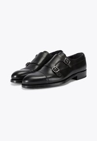 Czarne skórzane buty z podwójnym zapięciem typu monk strap, gładką fakturą, zaokrąglonym noskiem i niskim, ładnie ułożonym obcasem. Obecne są srebrne klamry.