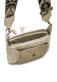 Beige Leder- und Canvas-Umhängetasche mit gemustertem Riemen, Reißverschlussfach und Quasten-Detail; verfügt über eine Außentasche und ein florales Innenfutter.