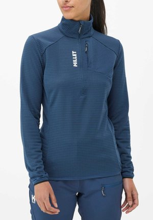 Pull en bleu marine avec col haut, fermeture éclair quart, motif texturé et poche poitrine. Présente un logo blanc sur le devant.