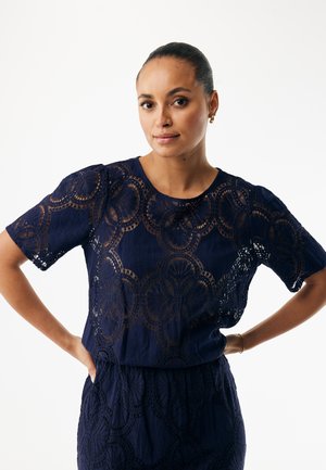 Marineblå blonder top med runde mønstre og korte ærmer. Tekstureret stof med gennemsigtige sektioner, designet til en afslappet pasform.