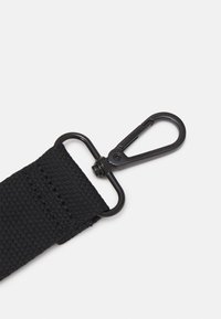 Sangle en tissu tissé noir attachée à un fermoir pivotant en métal noir avec un crochet à ressort sur fond blanc.