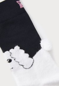 Black and white socks with a fluffy white dog design, featuring a textured white pom-pom, and a pink accent on the cuff.