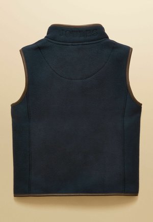 Temno modra brezrokavnik iz flisa z visokim ovratnikom, rjavim robom na razporkih rok in robu ter z vezenim napisom "JOULES" na zadnjem delu ovratnika.