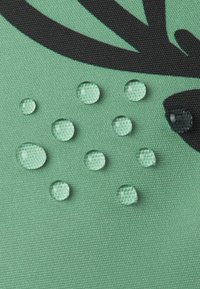 Zielona tkanina o teksturze z czarnym wzorem, na którym znajdują się liczne przezroczyste krople wody w różnych rozmiarach.