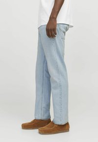 Lys blå denim straight-leg jeans med en falmet finish, med frontlommer og livvidde, parret med brune ruskinds slip-on sko.