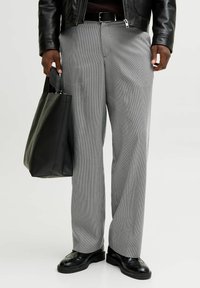 Hallide ruudulised püksid lõdva lõikega, kombineeritud musta nahast kotiga ja poleeritud mustade kingadega, millel on keerukad mustrid.