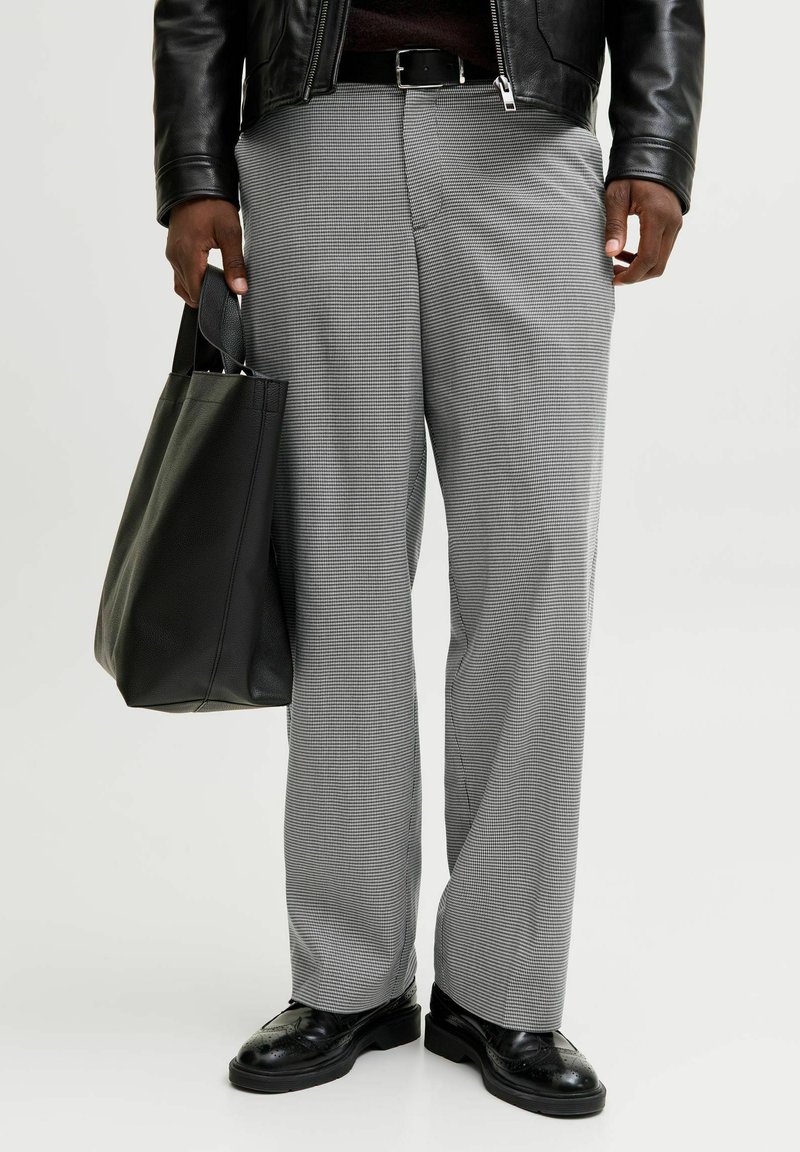 Hallide ruudulised püksid lõdva lõikega, kombineeritud musta nahast kotiga ja poleeritud mustade kingadega, millel on keerukad mustrid.