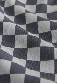 Gestrickter Stoff mit einem karierten Muster aus abwechselnd dunkelgrauen und hellgrauen Quadraten, mit weicher Textur und leichtem Glanz.