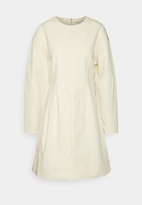 Vestido de color crema con mangas largas, escote estructurado y cintura ajustada que se abre en una falda acampanada. Tejido texturizado. Espalda con cremallera.