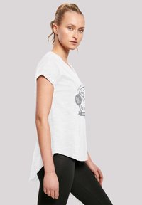 White short-sleeve t-shirt with a v-neck, featuring a graphic print in gray. Lightweight fabric with a rounded hem, worn with black leggings.