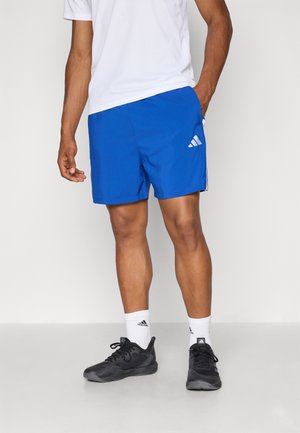 Blue athletic shorts with a smooth texture, featuring three white stripes and the Adidas logo on the left side. Worn with white socks and black shoes.