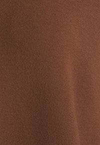 Tissu côtelé brun avec une texture lisse, présentant une épaisseur moyenne et un léger éclat, adapté à diverses applications vestimentaires.