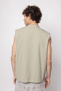 Sleeveless, light olive green top with a relaxed fit, featuring a simple neckline and textured fabric. No visible patterns or hardware.