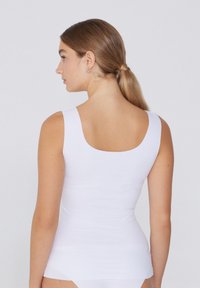 Weißes ärmelloses Tanktop mit rundem Rückenausschnitt, aus glattem Stoff, enganliegendes Design, minimalistischer Stil ohne erkennbare Muster.