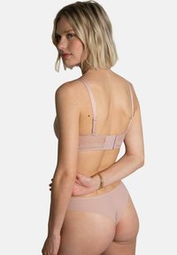Soutien-gorge en dentelle rose avec des fines bretelles, présentant une texture lisse et une fermeture à crochets. Accompagné de culottes sans coutures assorties.