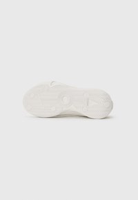 White sneaker sole with textured rubber, featuring a herringbone pattern and circular traction points. Smooth finish, minimal design.