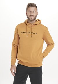 Hooded sweatshirt i sennepsgul med en sort "ENDURANCE" tryk på forsiden, lavet af blødt stof med en standard pasform og kængurulomme.