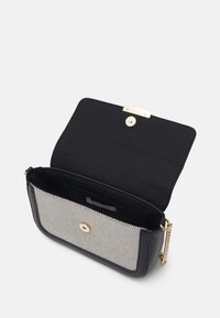 Borsa a spalla nera con fronte in rete metallica, dettagli dorati e tracolla a catena. La patta aperta rivela un interno in tessuto nero con etichetta.