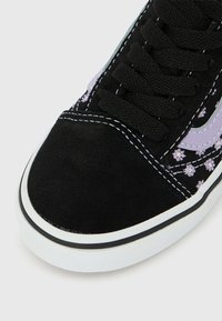 Μαύρο αθλητικό παπούτσι με λευκή σόλα, μαύρα κορδόνια, λευκή ραφή και μοβ λουλουδάτο σχέδιο στην πλευρική επιφάνεια.