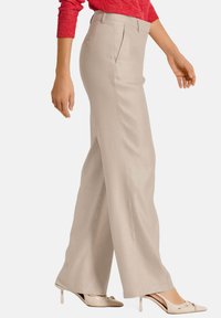 Beige wijde broek met een gladde textuur, twee voorplooien en een middelhoge tailleband, gecombineerd met naakte hoge hakken.